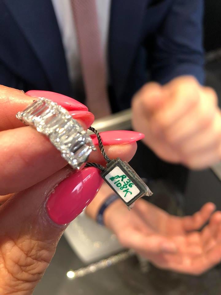 Hand with manicured pink nails holding a ring, price tag, Salon Privé 2018