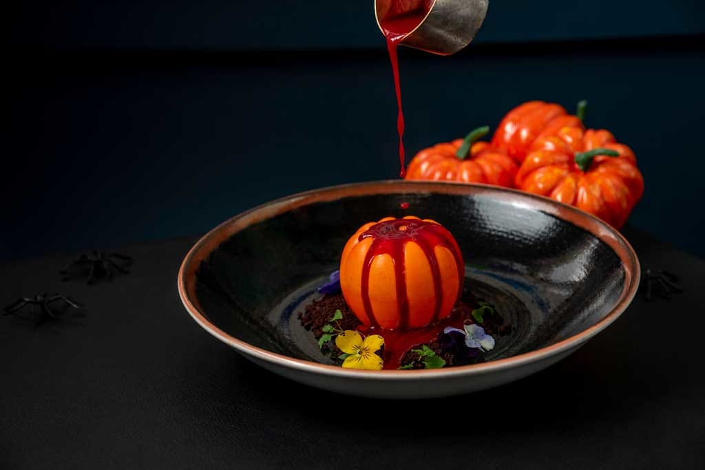 Halloween decor, pumpkin shaped dessert with blood red sauce