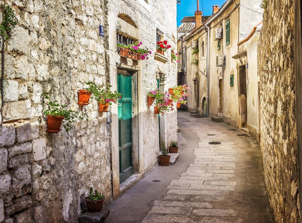 Narrow cobbled street in Kotor Old Town, Montenegro, with stone houses and flower pots on walls