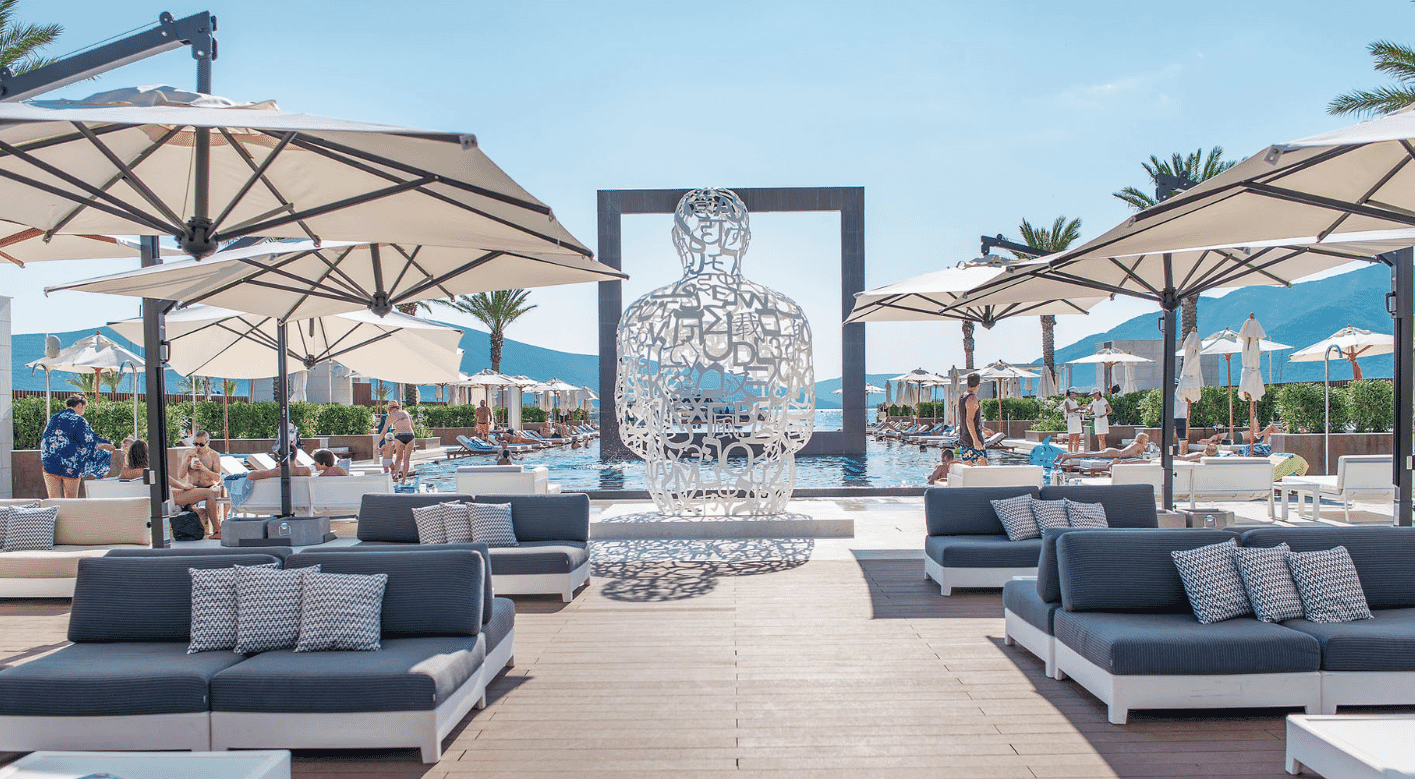 Regent Porto Montenegro hotel, yacht club pool with modern sculpture, umbrellas and sun loungers