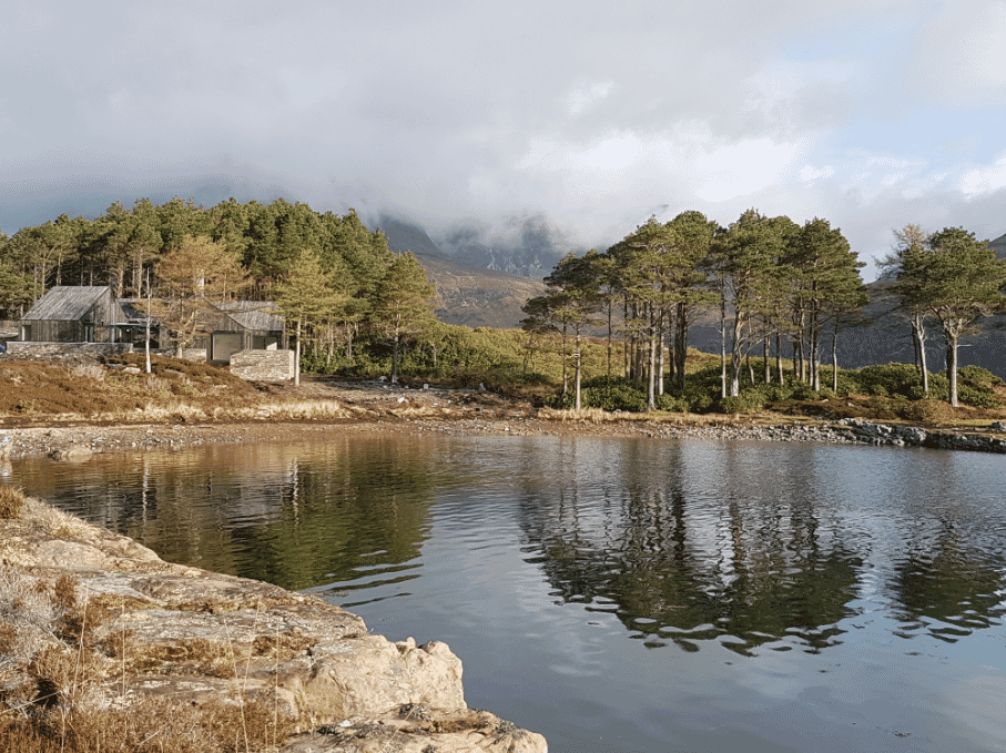 Lochside House on waterside with forest, mountains and clouds in background RIBA Awards 2018