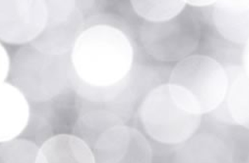 A soft, blurred background with overlapping circles of light in shades of white and gray, creating a bokeh effect reminiscent of Christmas presents. The image has a dreamy and abstract appearance.