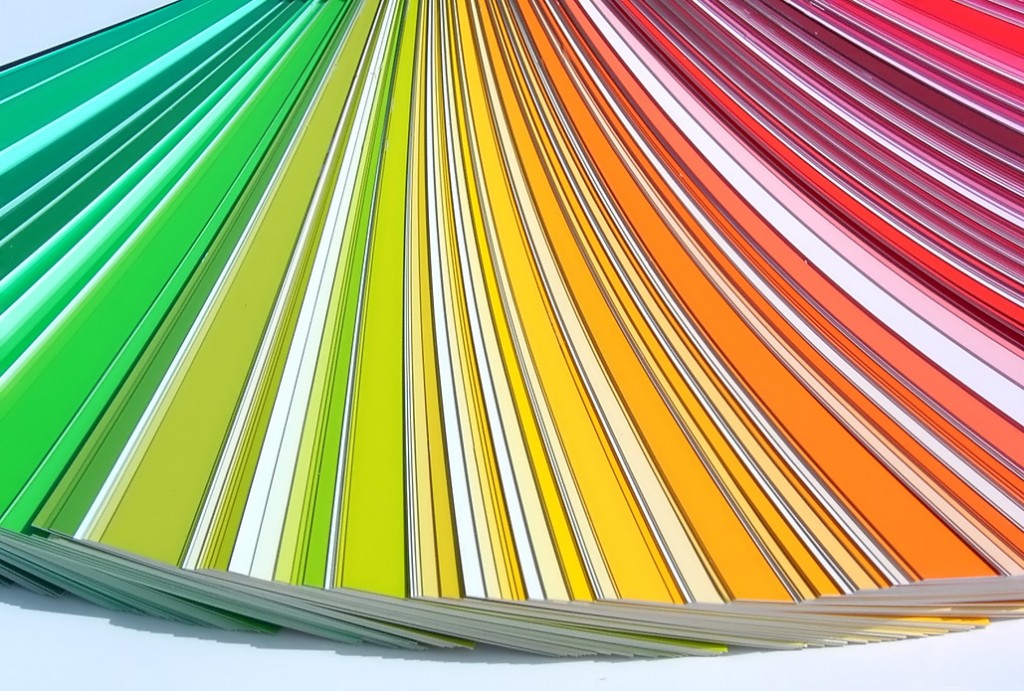 A colorful fan-like spread of paper samples displaying a gradient from green to red, prominently showing their vivid and vibrant hues. Perfect for brightening up your home office while working from home, the arrangement forms a visually appealing spectrum with each sheet slightly overlapping the next.