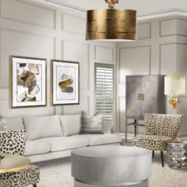 A modern living room features a light grey sofa with patterned cushions, a round coffee table, and two leopard-print chairs. The walls are adorned with abstract art, and a gold pendant light hangs from the ceiling. Through an online consultation, this interior design also includes a grey cabinet and a floor lamp to complete the decor.