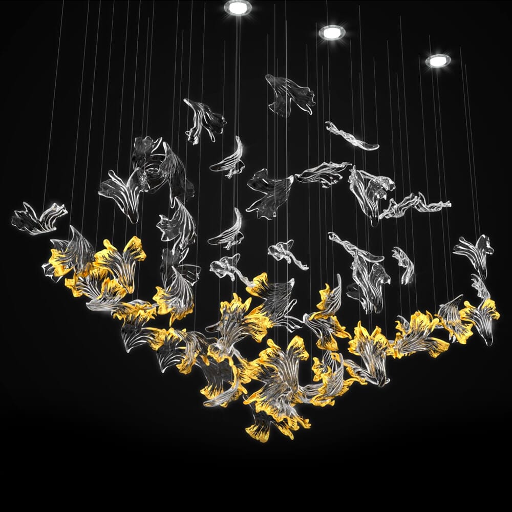 An elegant chandelier features a dynamic design of hanging glass elements resembling flowing fish. Sparkling beneath soft, glowing lights in shades of clear and warm yellow, the illuminated chandelier creates an artistic effect against a dark background.