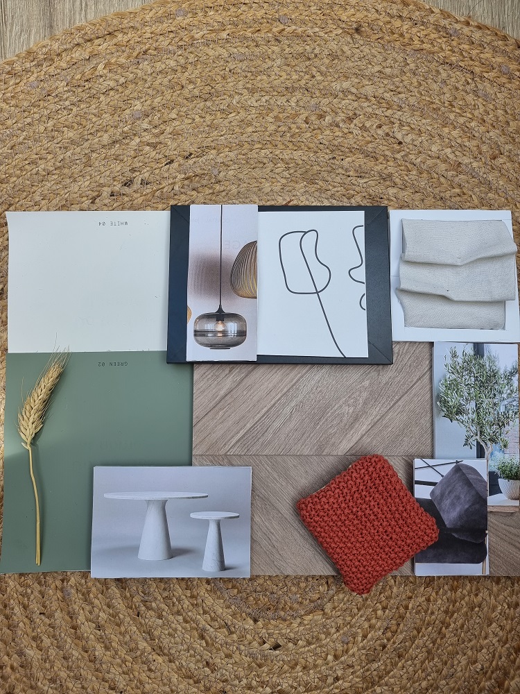 A flat lay image showcasing a variety of materials and inspirations from an interior design course on a woven mat. Items include colored paint swatches, fabric samples, a leafy branch, minimalist sketches, and photos of furniture. A knit swatch and geometric wooden tile are also present.