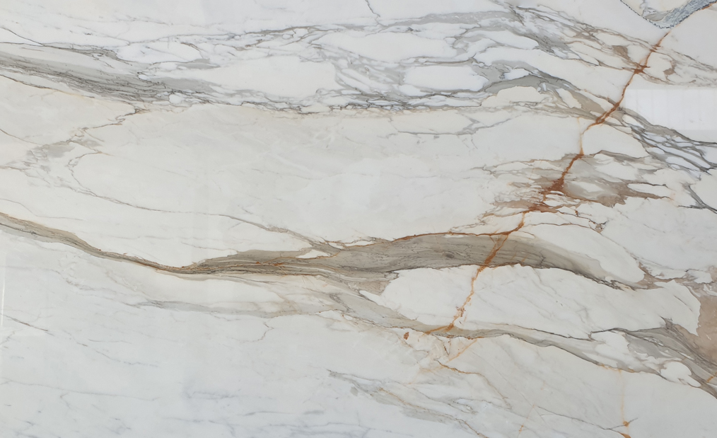 A close-up view of a white marble surface featuring intricate, natural veining in shades of gray and beige with streaks of rust-colored lines throughout. The polished texture highlights the stone's unique patterns and smooth finish.