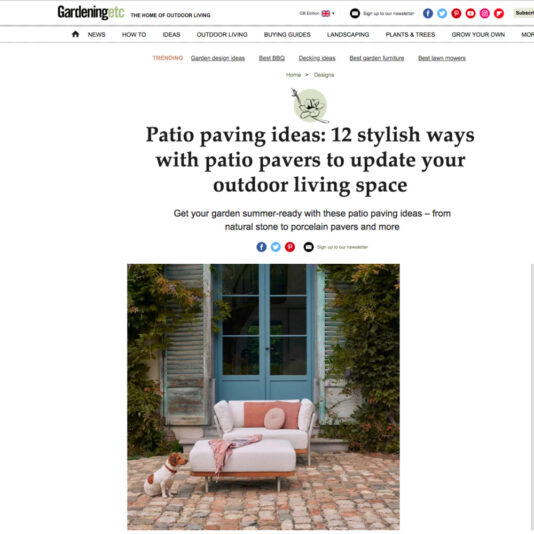 Screenshot of a Gardening Etc. webpage titled "Patio paving ideas: 12 stylish ways with patio pavers to update your outdoor living space." Below the title is a patio scene with a sofa adorned with pillows and a small dog standing on the paving stones.