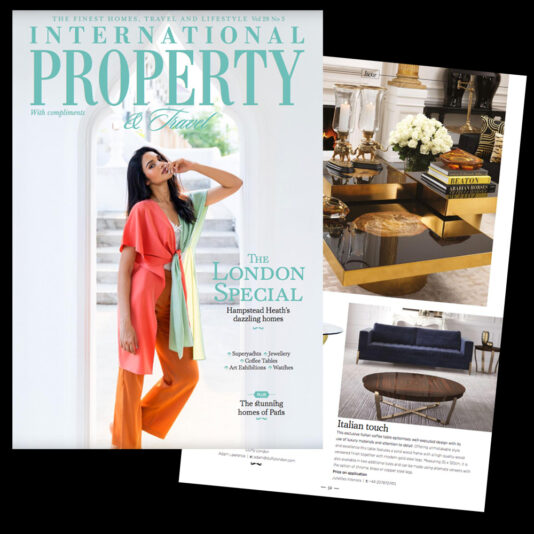 A magazine cover titled "International Property & Travel" features a model posing in a stylish outfit. Behind, there is a photo spread showcasing luxurious home interiors, including a coffee table and a plush living room with contemporary decor.