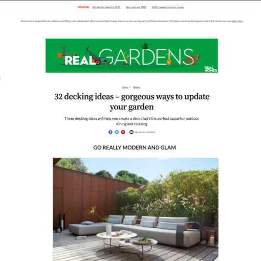 A web page from Real Homes titled "32 decking ideas – gorgeous ways to update your garden." It features a stylish outdoor deck setup with a modern lounge area, including a circular sofa with cushions, a coffee table, and potted plants in the background.