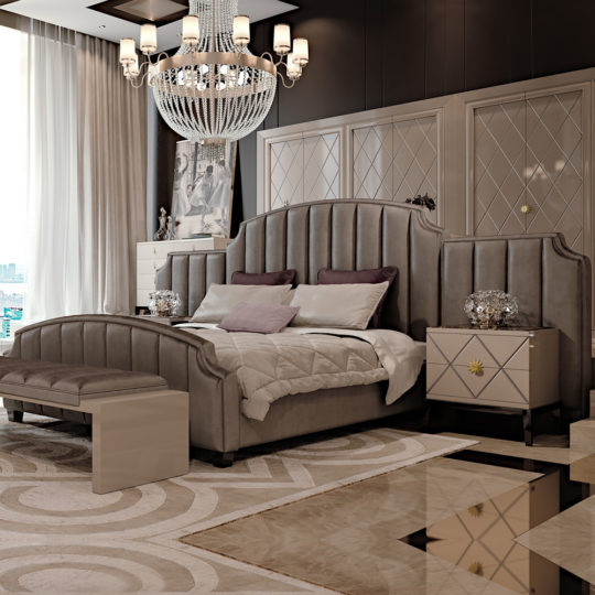 A luxurious bedroom features a large, upholstered bed with mauve and white pillows, flanked by elegant nightstands. Above hangs a grand chandelier. The modern room is decorated with neutral tones and art deco interior design elements, accented with geometric patterns on the wall and rug.