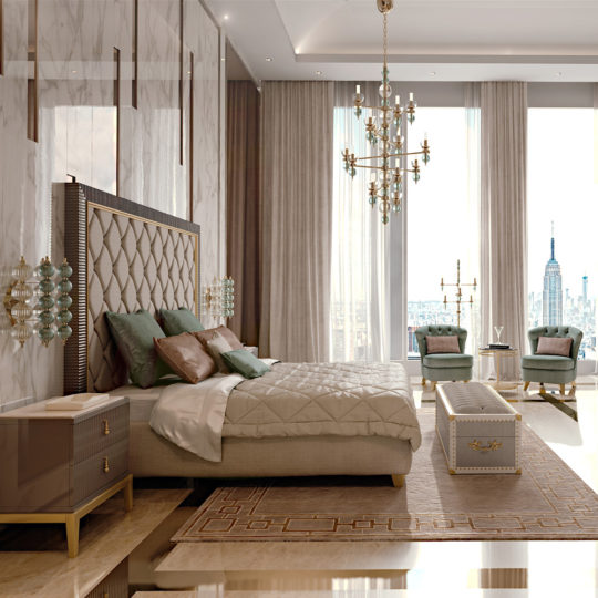 A luxurious bedroom features a large, upholstered bed with green pillows and a beige quilt. Flanked by nightstands, the room’s art deco interior design boasts a chandelier, a bench at the foot of the bed, armchairs, and floor-to-ceiling windows with city skyline views. Neutral, elegant decor enhances the space.