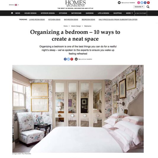 A webpage from "Homes & Gardens" featuring an article titled "Organising a bedroom – 10 ways to create a neat space." The page displays a well-organized bedroom with floral wallpaper, built-in shelving, and a neatly made bed with pastel bedding.