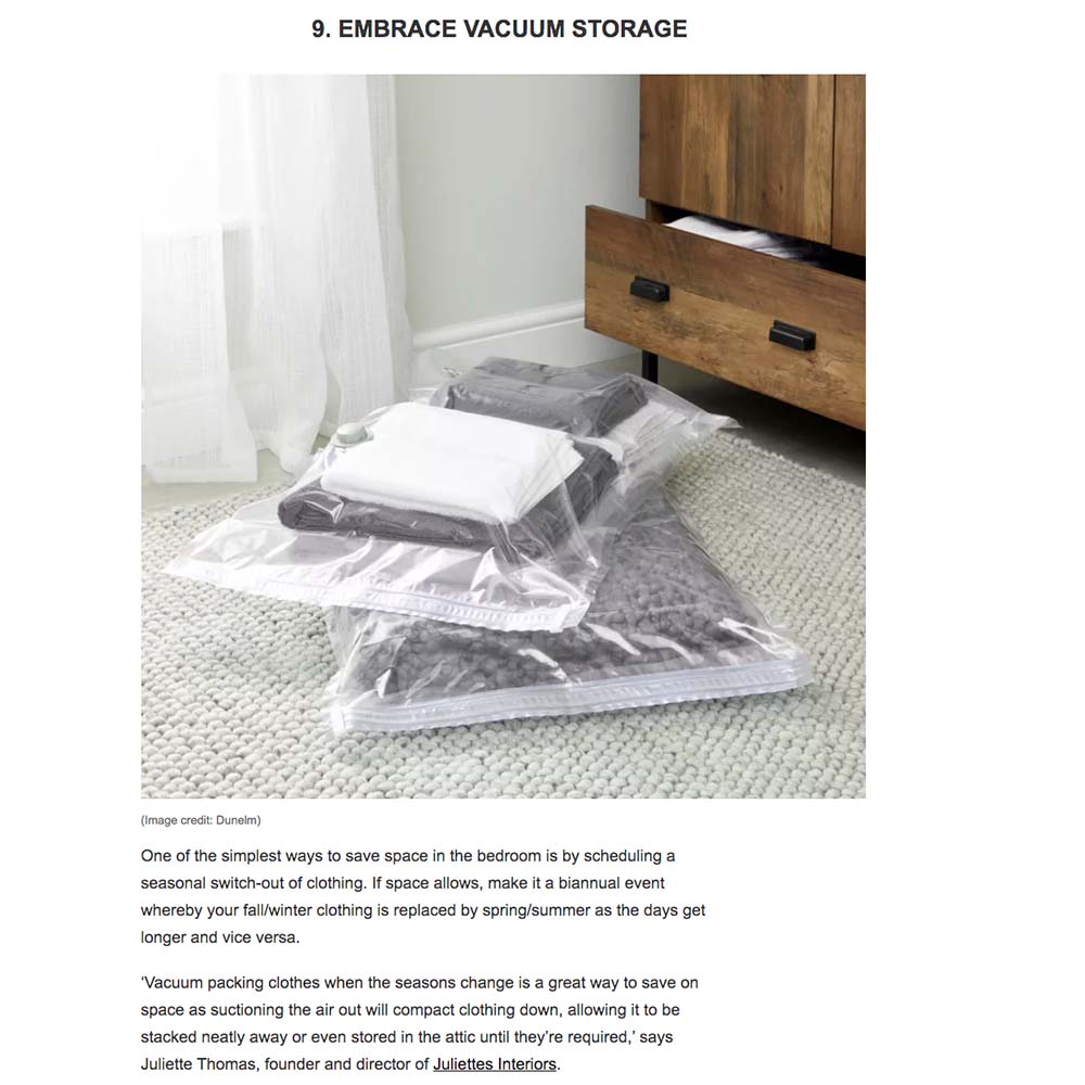 A bed with a wooden side table beside it graces the room. On the floor, three vacuum storage bags filled with clothes are neatly stacked, showcasing an efficient use of space. Homes & Gardens enthusiasts will appreciate the accompanying text paragraphs outlining the benefits of vacuum storage for seasonal clothing.