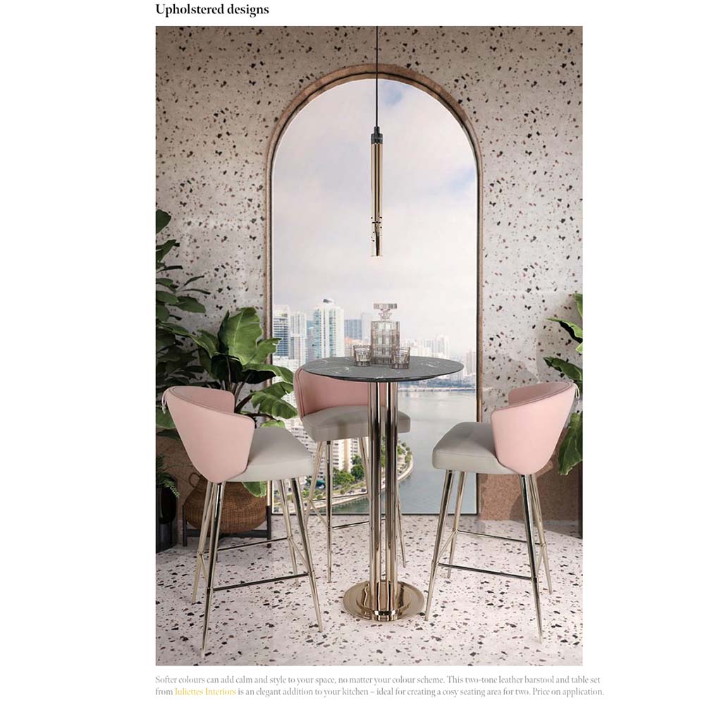 A modern interior decor scene featuring a tall round table with a glass top and three high-back chairs upholstered in dual-tone beige and pink graces these three rooms. The setting is complemented by large green plants and a window view of high-rise buildings and a water body.