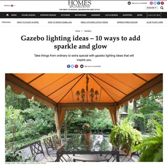 A webpage from "Homes & Gardens" features an article titled "Gazebo lighting ideas – 10 ways to add sparkle and glow." The image shows a stylish gazebo with a wooden dining table, surrounded by lush greenery, and illuminated by cozy string lights. Discover more at Homes & Gardens.