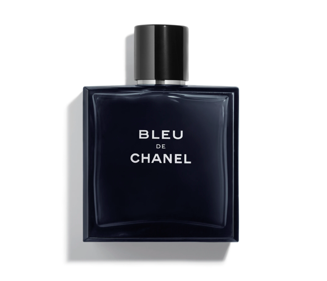 A sleek, rectangular, dark blue glass bottle of "Bleu de Chanel" perfume with a shiny black cylindrical cap. The bottle features white text on the front displaying the fragrance name and brand. An elegant choice, it ranks among the best luxury Father's Day gifts. The background is white and the bottle casts a subtle shadow.