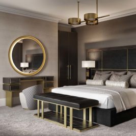 A modern bedroom with a large bed featuring a tufted headboard, two bedside tables with lamps, and a round mirror above a vanity table with a padded chair. The room's neutral color scheme, gold accents, and sophisticated details evoke the refined style of a gentleman's luxury home office.