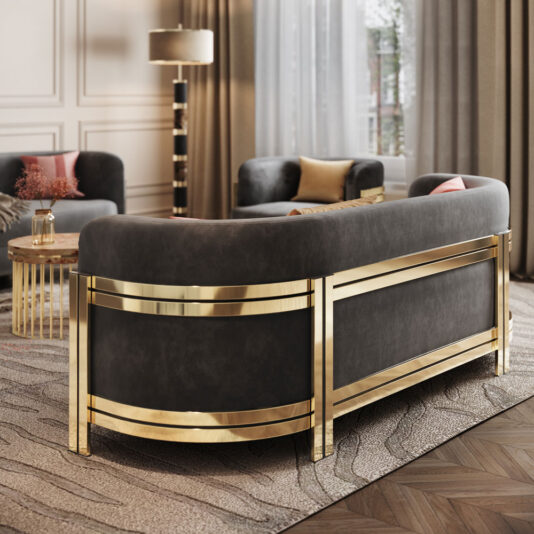 Modern Curved Sofa With Brass Frame A luxurious living room features the Modern Curved Sofa With Brass Frame in sleek black, enhanced with gold accents. It is complemented by a matching armchair and a round glass coffee table with a gold base. The room boasts light-colored walls, a tall floor lamp, a large window adorned with sheer curtains, and a textured rug.