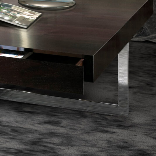 Modern Square Coffee Table With Drawers A Modern Square Coffee Table With Drawers, featuring dark wood and a metal frame, graces a textured gray carpet. A sleek, curved silver object sits elegantly on the table's surface.