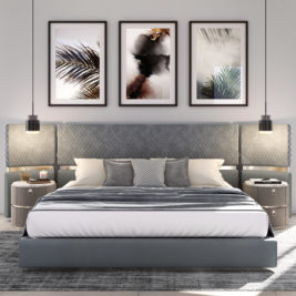A deluxe modern bedroom features the Deluxe Contemporary Curved Bed with a grey upholstered headboard and multiple pillows. Two round grey bedside tables flank the bed, each with a hanging pendant light above. Three framed abstract artworks adorn the wall behind this contemporary setup.