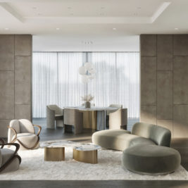 A modern living room with neutral tones features a curved green sofa, two marble coffee tables, and an armchair with wooden accents, embodying the Organic Modern Style. A dining area with a circular table and contemporary chairs is seen in the background, highlighted by a minimalist chandelier. Floor-to-ceiling windows let in natural light.