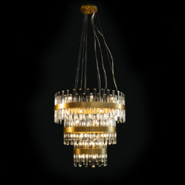 A luxurious, tiered chandelier with a modern design featuring multiple levels of cylindrical glass prisms and gold accents, suspended by thin wires against a dark background. This piece of affordable luxury lighting emits a warm, elegant glow.