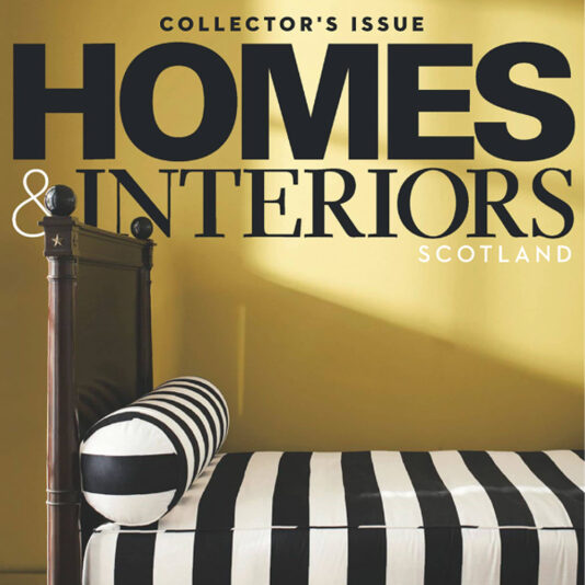 Cover of Homes & Interiors Scotland magazine, Collector's Issue. Feast your eyes on a bed with black and white striped bedding and a matching bolster pillow. The focus is on the clean, modern design and bold stripes set against a vibrant yellow wall.