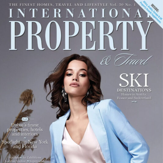 Cover of International Property & Travel magazine featuring a woman in a light blue blazer over a white top. Text highlights "Ski Destinations" in Austria, France, and Switzerland, with additional features on Dubai’s finest properties, exclusive designer beds, and a spotlight on New York and Florida.