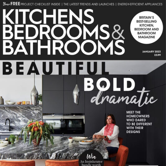 Cover of "Kitchens, Bedrooms & Bathrooms" magazine, January 2023 issue. The magazine features a modern kitchen with bold, dramatic design elements. A woman in red and white sits on a barstool at a marble island. Text highlights the future of our homes with a project checklist and reader offers.