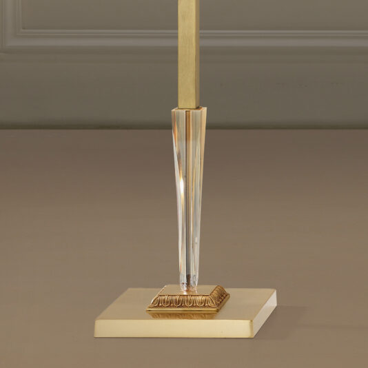 A close-up image of the lower part of the Luxury Classical Floor Lamp. The stylish, modern lamp features a square, gold-colored base with a central vertical rod extending upwards. The rod has a clear, faceted section adding an element of elegance and sophistication to the overall design.