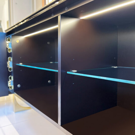 The Luxury Art Deco Style Sunburst Sideboard is shown with its door open, revealing a dark wood interior, glass shelves, metal hinges, and built-in LED strip lighting that highlights its modern and clean design.