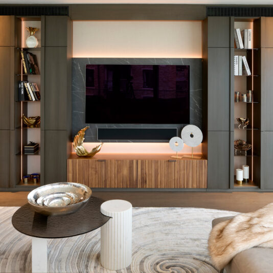 Tropical Leaf Basket Modern living room featuring a large wall-mounted TV, built-in shelves with books and decor, a wooden media unit, abstract sculptures, a round coffee table with a silver bowl on a patterned rug showcasing the Luxury Decorative Wave Ornament.