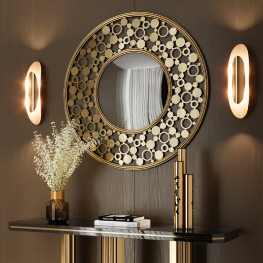 A Modern Round Convex Mirror with a gold geometric frame hangs above a black console table with gold accents, decorated with a vase of white flowers, two books, and two gold objects. Two wall sconces are on either side of the mirror.