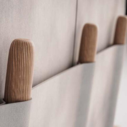 High End Contemporary Italian Bed Close-up of two wooden handles partially tucked into light grey fabric pockets, shown vertically against a soft, textured background—an elegant accent on the High End Contemporary Italian Bed.