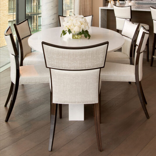 Oval dining table set with upholstered chairs in a riverside interior