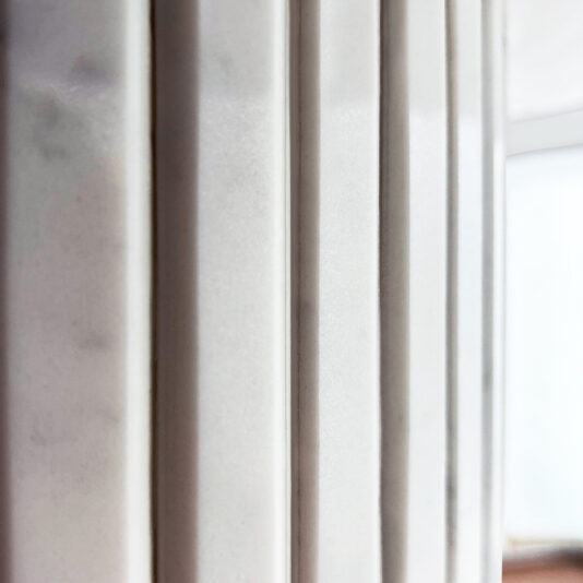 Fluted cylindrical pedestal detail beneath white quartz