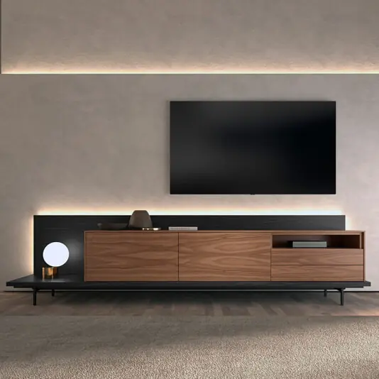 A modern living room with a wall-mounted TV above the Walnut Veneer Media Sideboard, decorated with accents and a round lamp, all set against a light-toned textured wall.