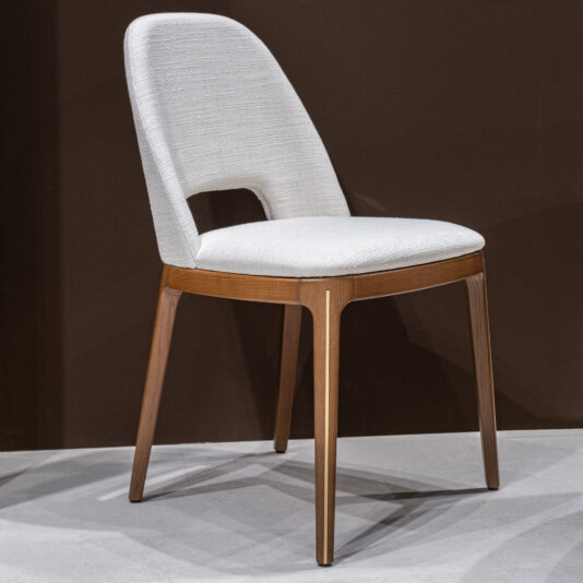 The Mid-Century Inspired Dining Chair features a white upholstered seat and backrest with a wooden frame and four angled legs, set against a dark brown background on a light-coloured floor.